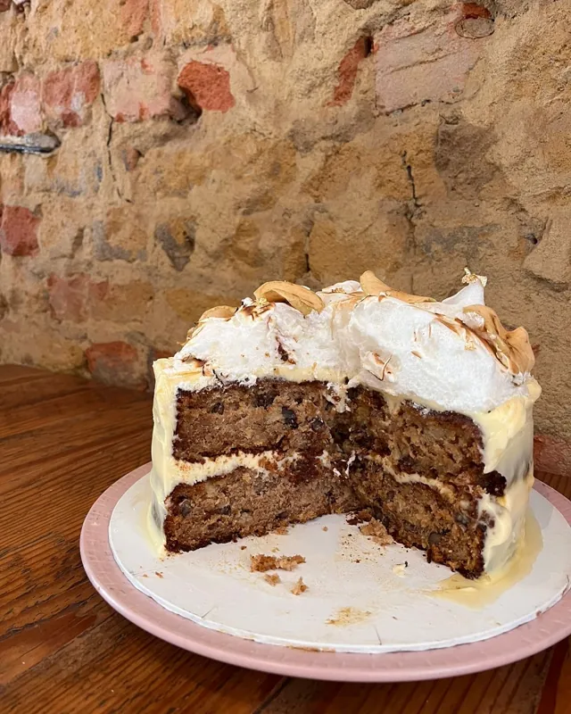 A cut honey cake with toasted meringue on a pink plate.