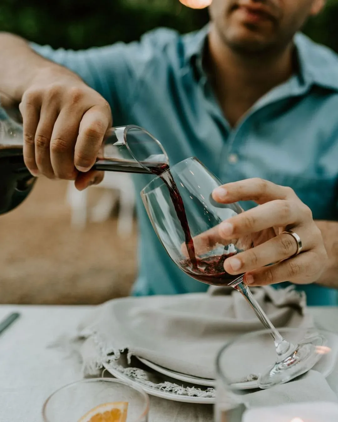 Red wine being poured at a garden table.