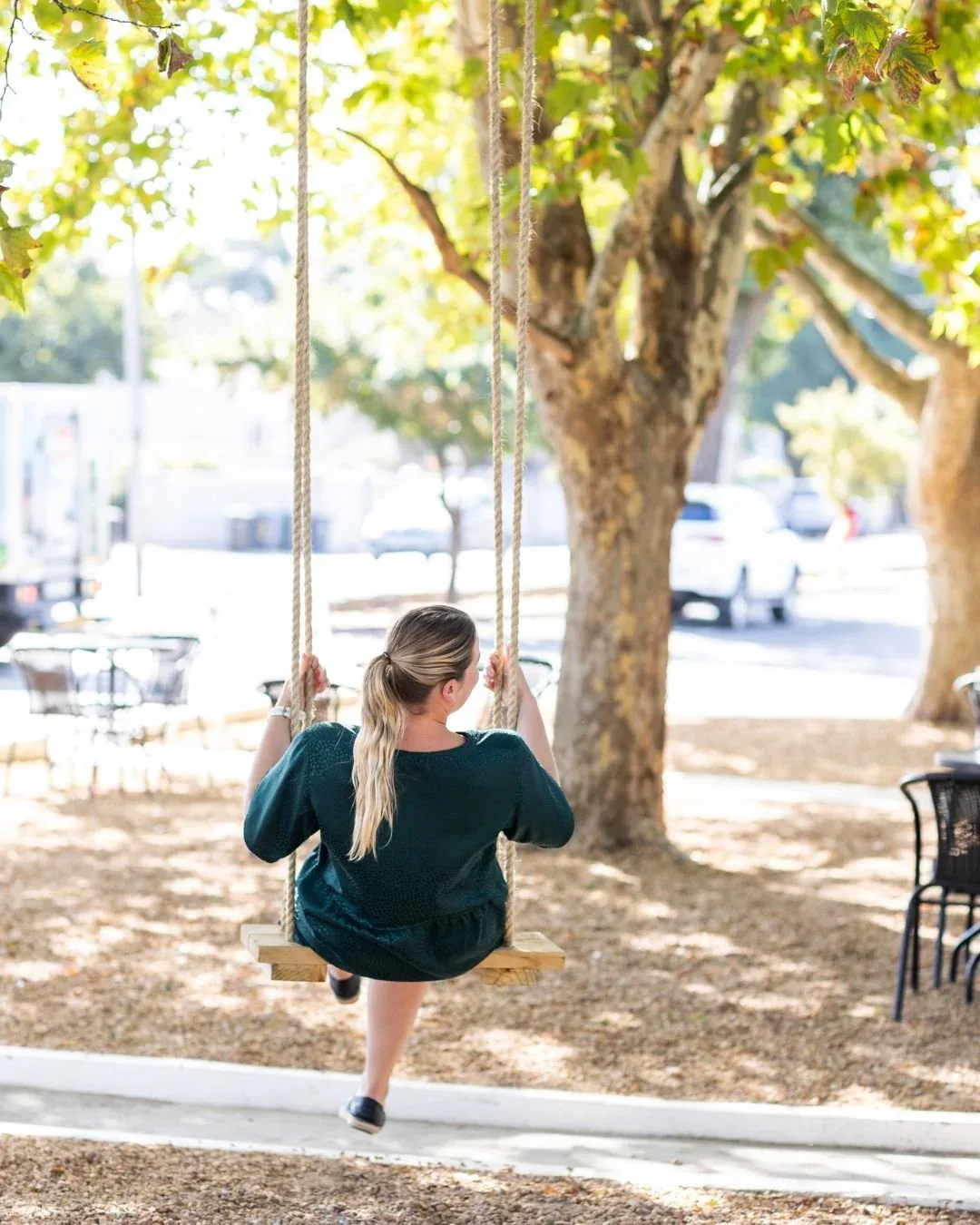 A woman on the garden swing that hangs from the plane tree.